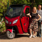 Viininpunainen Kontio Autokruiser -sähkömopoauto ulkona, vieressä pariskunta